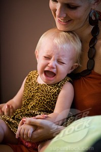 Baby girl crying while sitting on mother's lap